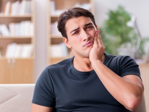 man holding jaw in pain before emergency dentistry