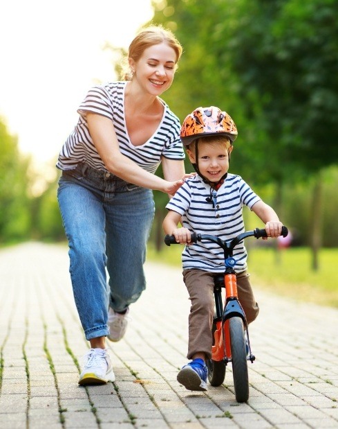 Mom teaching son to ride bike afte children's dentistry