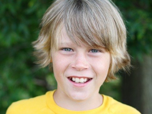 Boy in yellow shirt smiling after fluoride treatment