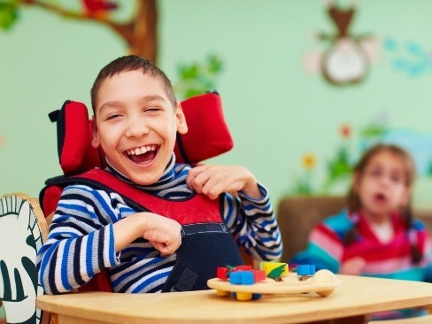 Child in wheelchair laughing after special needs dentistry