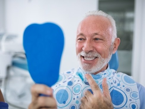 Man checking smile in blue mirror during dental visit
