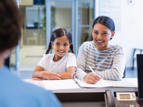 Mother and daughter at front desk of dental office