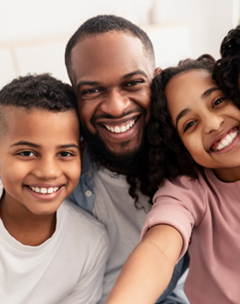Family of four smiling after visiting a Delta Dental dentist in Denver 