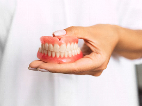 Dentist holding dentures in Denver