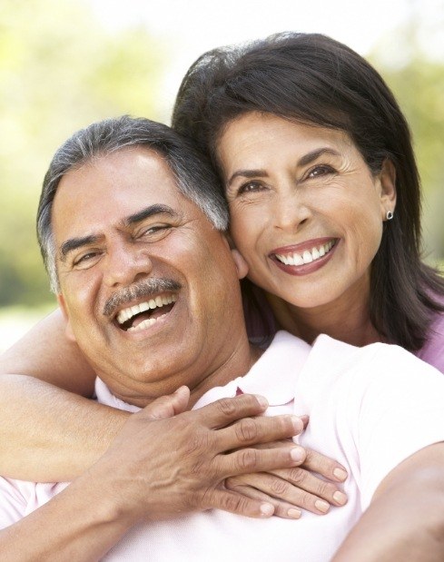 Husband and wife laughing together after emergency dentistry