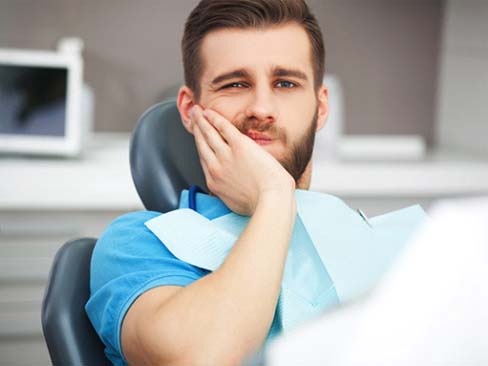 Man with a dental emergency in Denver touching his face