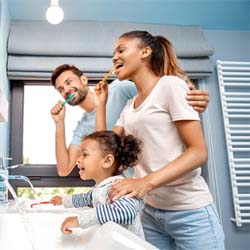 Family preventing dental emergencies in Denver by brushing their teeth