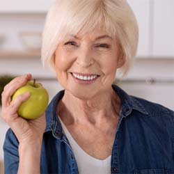 Smiling woman holding an apple in her kitchen