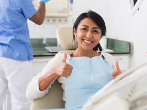 Woman in dental chair smiling and giving thumbs up