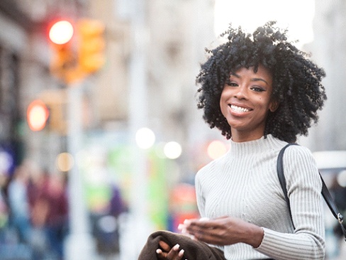 Woman with dental implants in Denver, CO walking and smiling