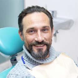 Man smiling while wearing a sweater in dental chair