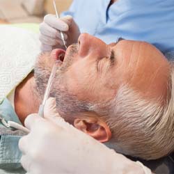 Man with grey hair laid back in dental chair