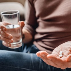 Close-up of person in brown shirt holding painkillers