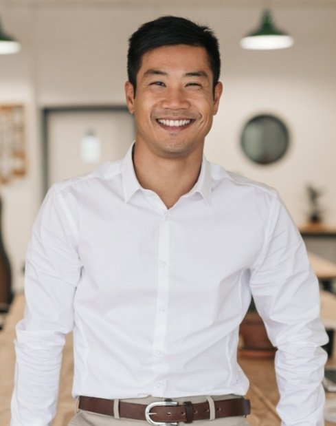 Man in white shirt smiling after replacing missing teeth with dental implants