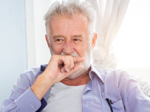 Man covering his smile before dental implant tooth replacement