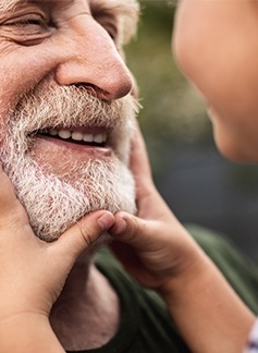 Grandpa and grandchild smiling after comprehensive family dental care