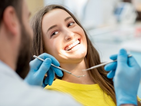 Woman in dental exam chair talking to dentist