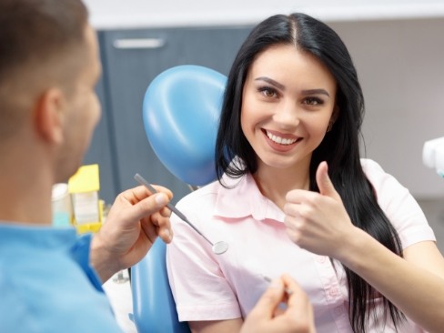 Woman in dental chair giving thumbs up