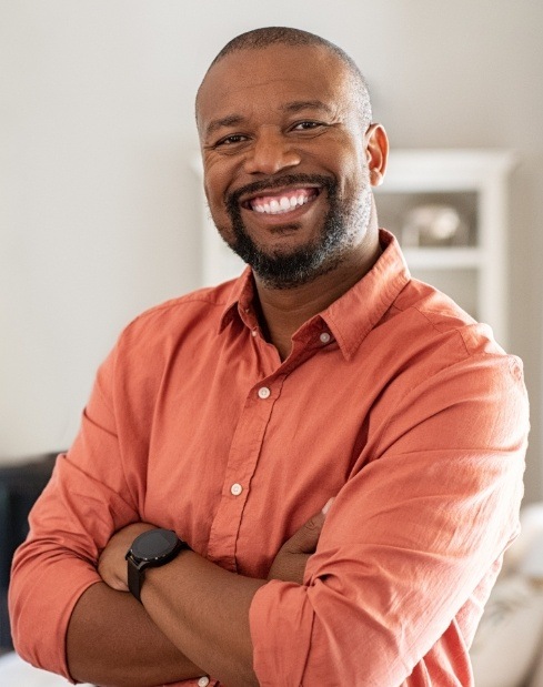 Man crossing arms and smiling after replacing missing teeth