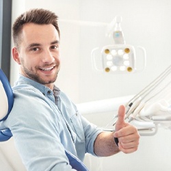 man in dental chair giving thumbs up