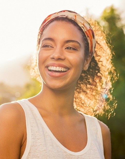 Woman smiling in sunlight after periodontal disease treatment