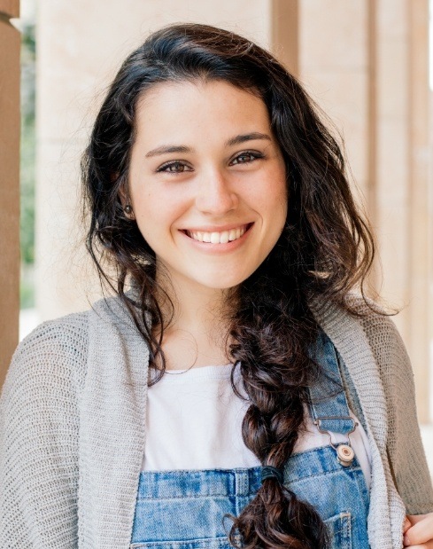 Woman in overalls smiling after wisdom tooth extraction