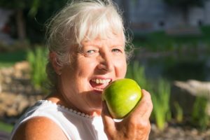 a woman with dentures eating an apple