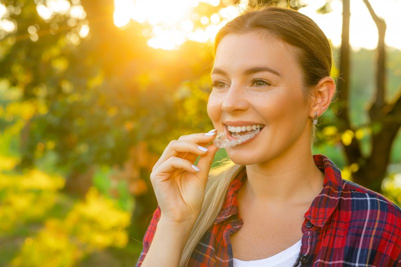 a woman putting on her Invisalign tray in Denver