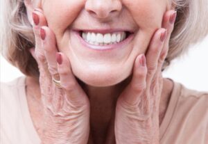 Older woman smiling wearing dentures.
