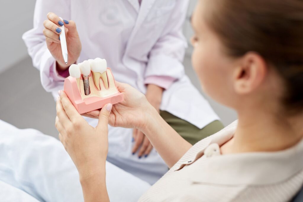 A dentist showing a woman a dental implant model